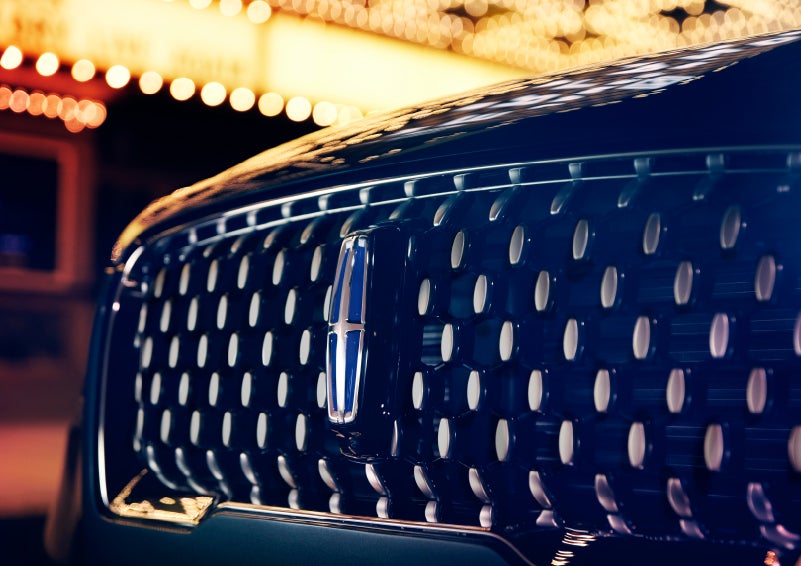 The Corsair Grand Touring grille shows floating chrome ovals that catch the glowing light of a theater marquee and frame the distinctive Lincoln Star | Mark Ficken Lincoln in Charlotte NC