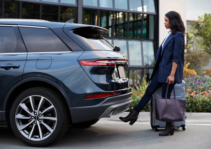 A woman with luggage and a bag opens the available hands-free liftgate by kicking her foot under the bumper | Mark Ficken Lincoln in Charlotte NC