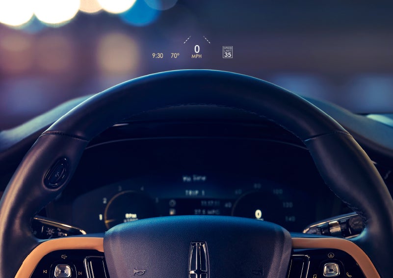 The available head-up display projects data on the windshield above the steering wheel inside a 2022 Lincoln Corsair as the driver navigates the city at night | Mark Ficken Lincoln in Charlotte NC